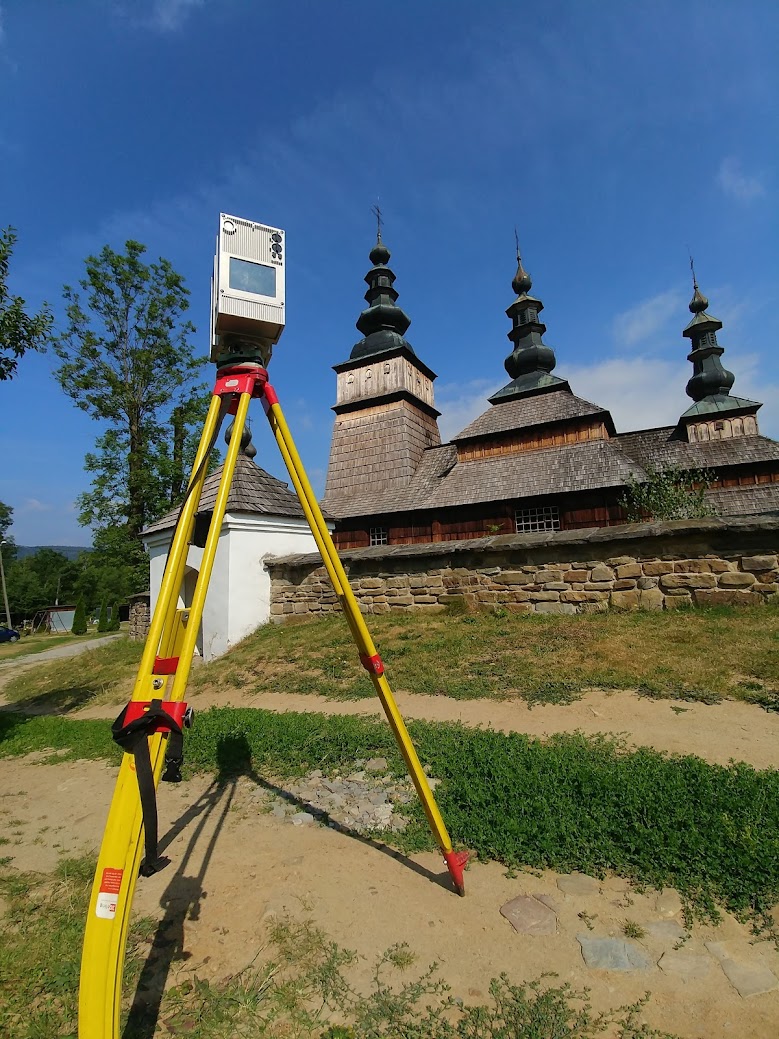 Terrestrial laser scanner mounted on tripod scanning historic wooden church
